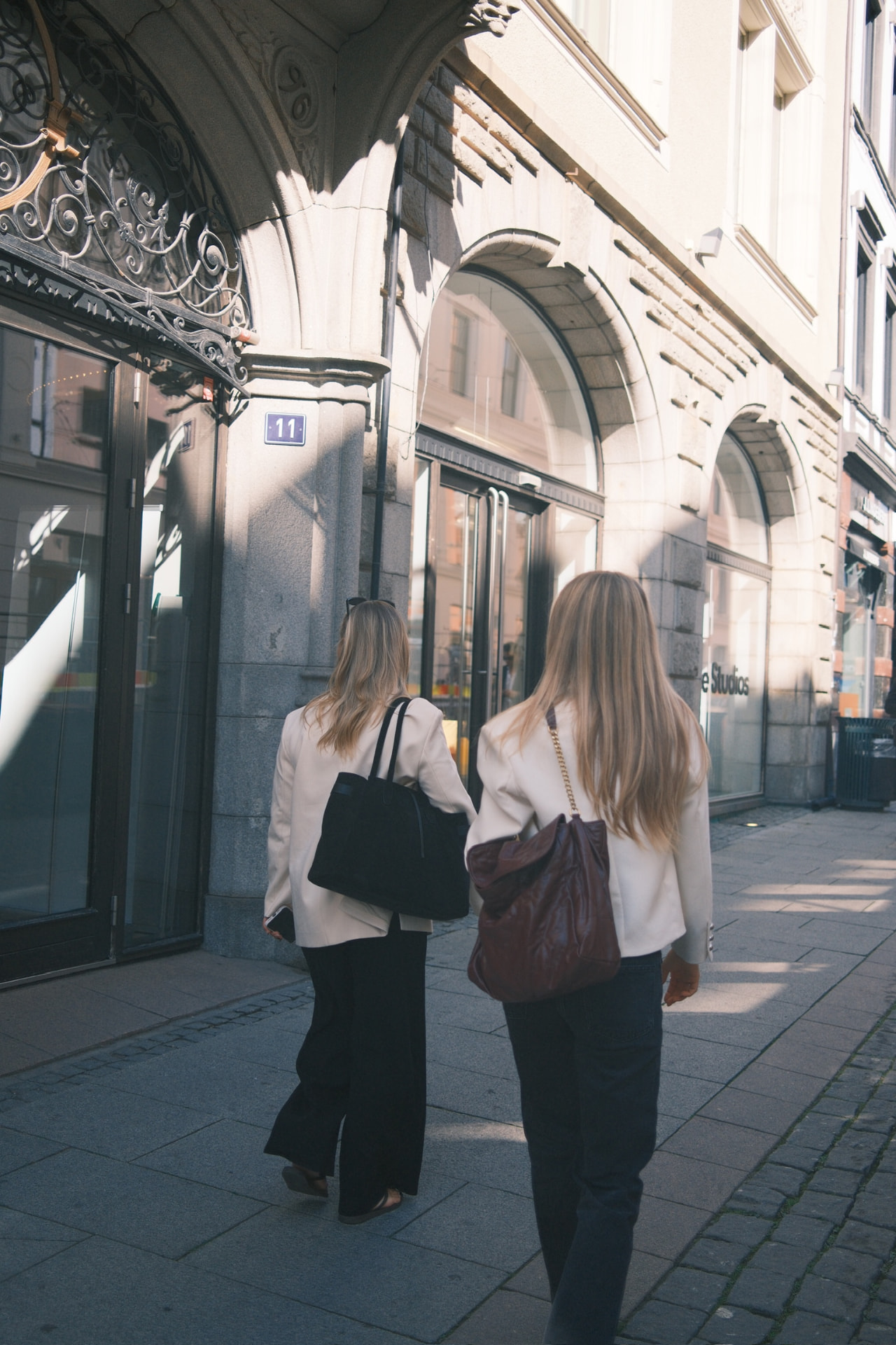 To kvinner med blonde hår som går bortover en brosteinet fortau i Oslo — KRE@IVE STUDIOS editorial
