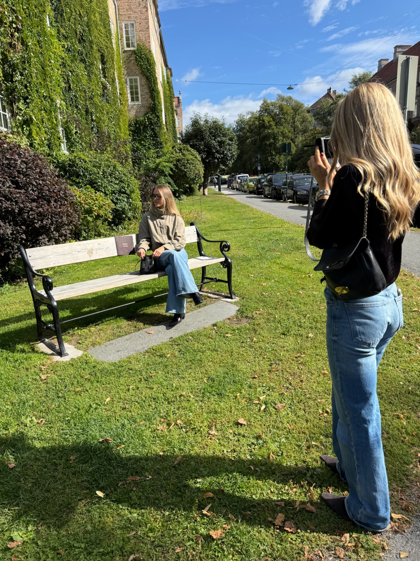 En kvinne som fotograferer en annen kvinne på en benk i solfylt Oslo — KRE@IVE STUDIOS editorial